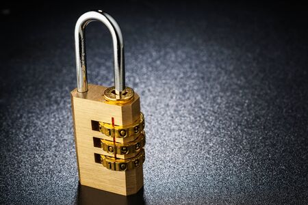 Brass lock with the code set on the dark surface. Texture background.の写真素材