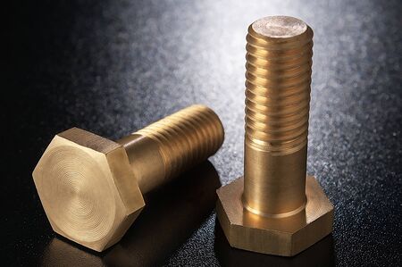 Brass bolts on a dark surface.の写真素材