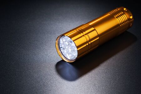 Golden flashlight on dark surface.の写真素材