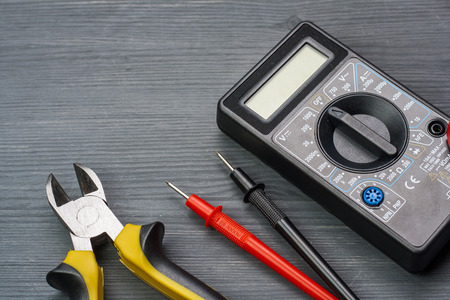 Multimeter and side cutters on a dark wooden background.の写真素材