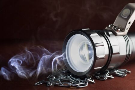 LED flashlight on a wooden table in the smoke.の写真素材