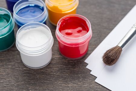 Looking down on three open paint cans of coloured paint stood on a shabby style wood floorの写真素材