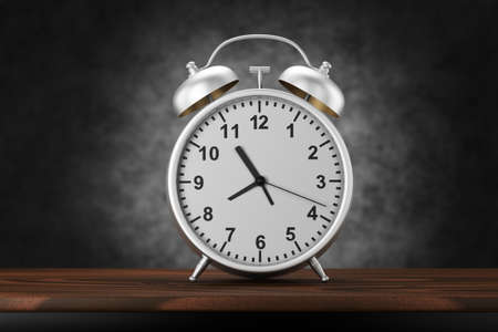 A vintage silver alarm clock stands on a wooden table on a dark concrete background. 3D render.の写真素材