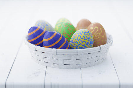 Colorful Easter eggs in a white basket on a wooden table. Easter still life. 3d rendering..の写真素材
