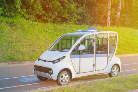 Electric police patrol car. A police electric golf cart sits empty with its special lights on on a bike path in a park or on the beach.の写真素材
