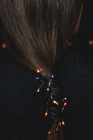 A close up of a womans face lit up at night with new year's multicolored garland. High quality photo