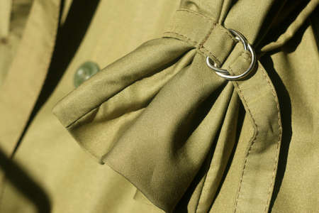 Elements and details of outerwear. Stylish green autumn trench coat. Stylish Clothing Design of Simple Vibrant Colorful green Shirt with No Print Close Up View. Modern Outwear Clothes. Background green. High quality photoの写真素材