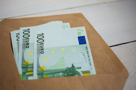 Bundle of Euro banknotes in an envelope on a wooden tableの写真素材