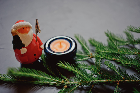 fir branch, candle and Santa Claus on dark background