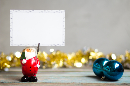 Santa Claus holding blank greeting card and Christmas decoration on wooden tableの写真素材