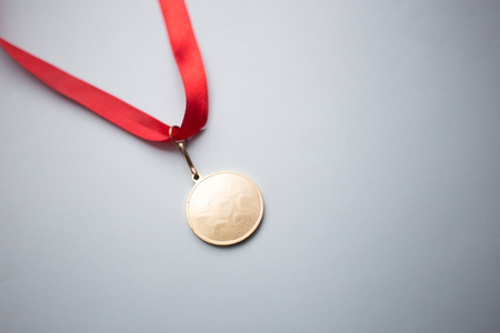 gold medal on a red ribbon on a blue background