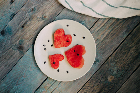 Slices of watermelon in the heart shape on vintage wooden table. Top viewの写真素材