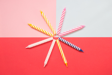 Multi-colored striped candles for birthday on the pastel colored background. Minimalism. Flat lay.の写真素材