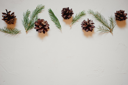 Christmas background with fir tree and decor, branches and cones. Top view with copy space, white plastered backgroundの写真素材
