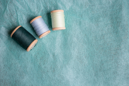 turquoise, green reels of thread on mint textured background, top view