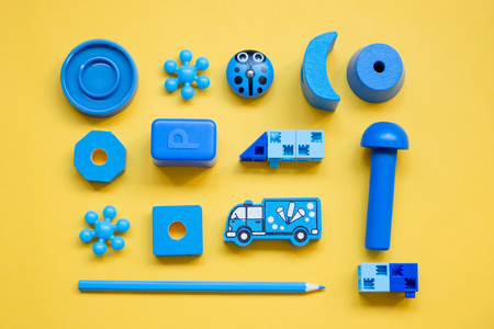 blue children's toys, laid out in a pattern on a yellow background, top viewの写真素材