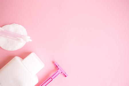 top view personal care products. white bottle, razor, ear sticks, cotton pads, toothbrush on pink background. copy spaceの写真素材