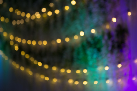 Multicolor cotton christmas garland floral and circle light bulb lighting, blue background. Colorful electric light bulbs illumination garland decoration for festive party celebration, blur backgroundの写真素材