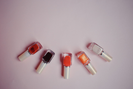 multi-colored nail polishes on pastel pink background, top view, Flat lay. Many round jars with multi-colored for nail polish.の写真素材