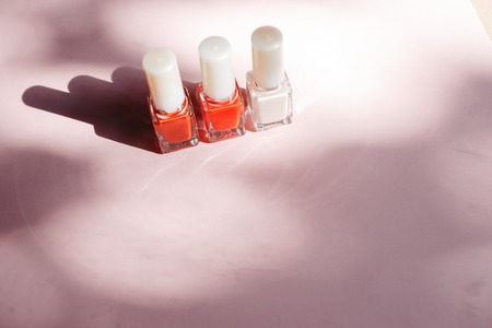 multi-colored nail polishes on pastel pink background, top view, Flat lay. Many round jars with multi-colored for nail polish.の写真素材