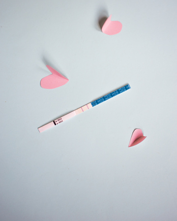 Positive pregnancy test with two strips and pink hearts. blue background, copy spaceの写真素材