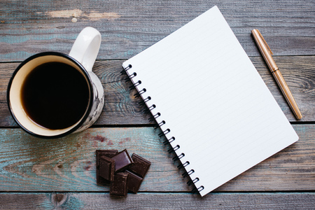 Cup of tea, chocolate and a notebook on a wooden table, flatlayの写真素材