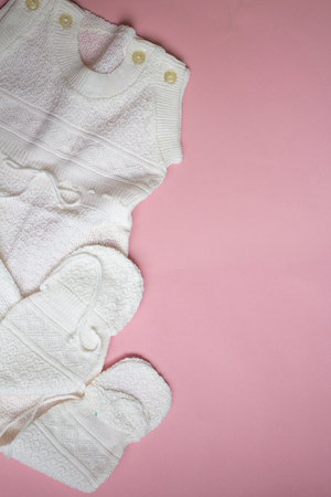 White baby's knitted clothes on pink background.の写真素材