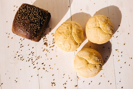 Assortment of baked bread on white wooden table background, hard light