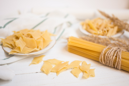 varieties of pasta on a white wooden table, spaghetti, Penne, maltagliati, local cuisineの写真素材
