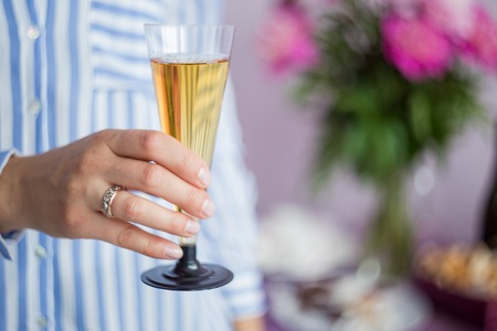 women's hand holding a glass of champagne on the background of the tableの写真素材