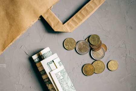 Cash dollars money, euro coins with a Kraft package on grayの写真素材