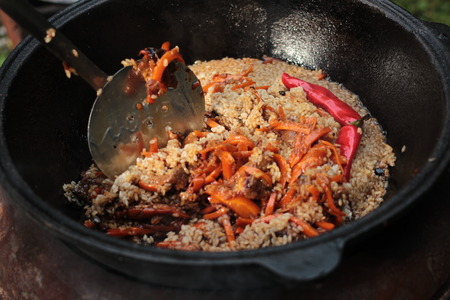Pilaf prepare in big black cast iron with chefs hand. National cuisineの写真素材