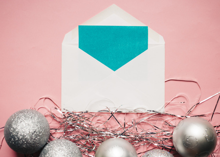 Christmas composition. Envelope with a card. Silver Christmas balls decorations on pink background. copy spaceの写真素材