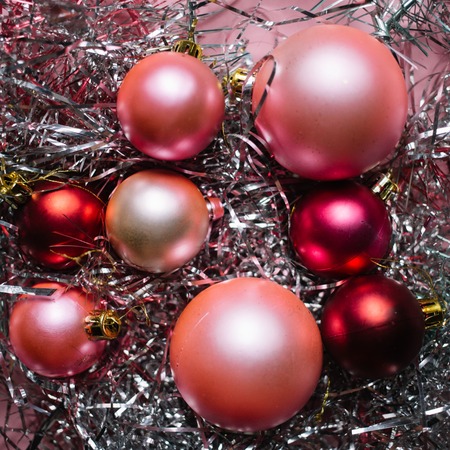 Christmas composition. Christmas red and pink decorations on pink tinsel background.