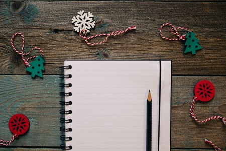 Empty Notepad and pencil, wooden Christmas decor, New Year, dark wooden flat lay frame. Winter...