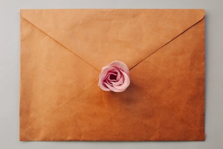 top view an old brown envelope, pink rose flower on a blue background. Minimal Flat layの写真素材
