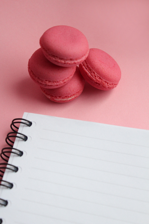 Four living coral macaroons, empty notebook on a pink backgroundの写真素材