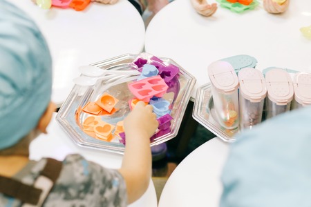 hands of a child, master class in cooking chocolate, folding fruit and chocolate on molds