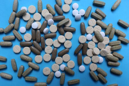 medicine pills, tablets and capsules on blue background