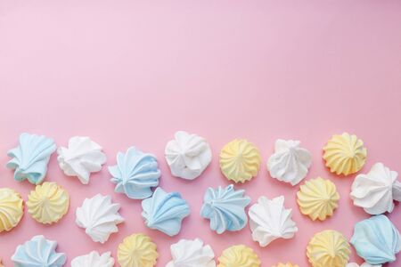 Multicolored meringue on a pink pastel background. Delicious colorful handmade dessert.