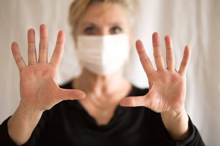 Senior woman wearing mask, shows clean hands and show stop hands gesture for stop corona virus outbreak. Coronavirus and epidemic virus symptoms.の写真素材