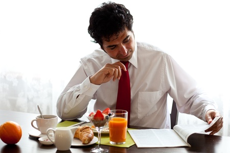 Man reads magazine while having a breakfastの写真素材