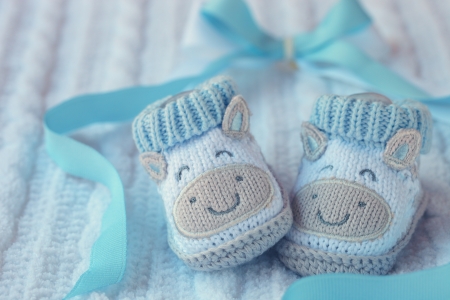 Knitted baby shoes for boy on a blue background  Greeting card の写真素材