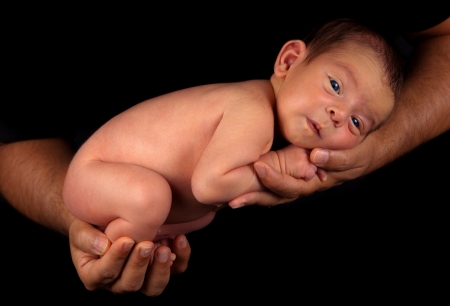 Father holding tiny cute newborn baby boy  Studio shot, over black background の写真素材