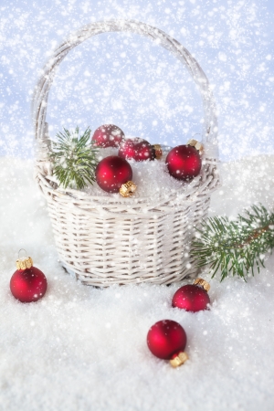 Christmas decoration - red balls in the basket with snow and branch of pineの写真素材