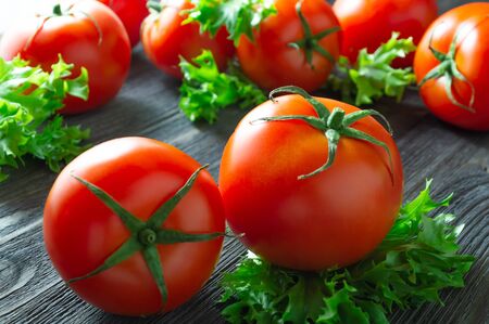 Fresh tomatoes and lettuce on dark wooden table.の写真素材