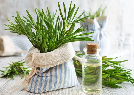 Rosemary essential oil and fresh rosemary in decorative pouch on old wooden table.の写真素材