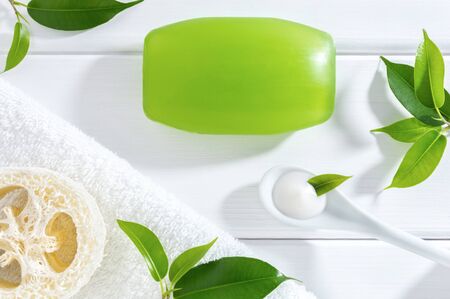 Natural homemade or SPA skin care cosmetics: glycerine soap, cream, loofah sponge and towel on white wooden background.の写真素材