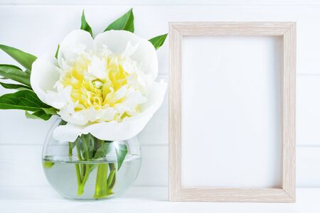 White peony flower in vase on white wooden background with mockup or copy space.の写真素材