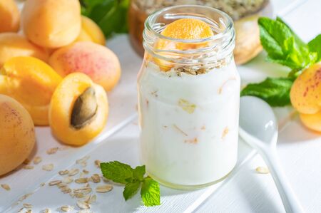 Oatmeal milkshake, smoothie or yogurt with fresh apricot on a white wooden table.の写真素材